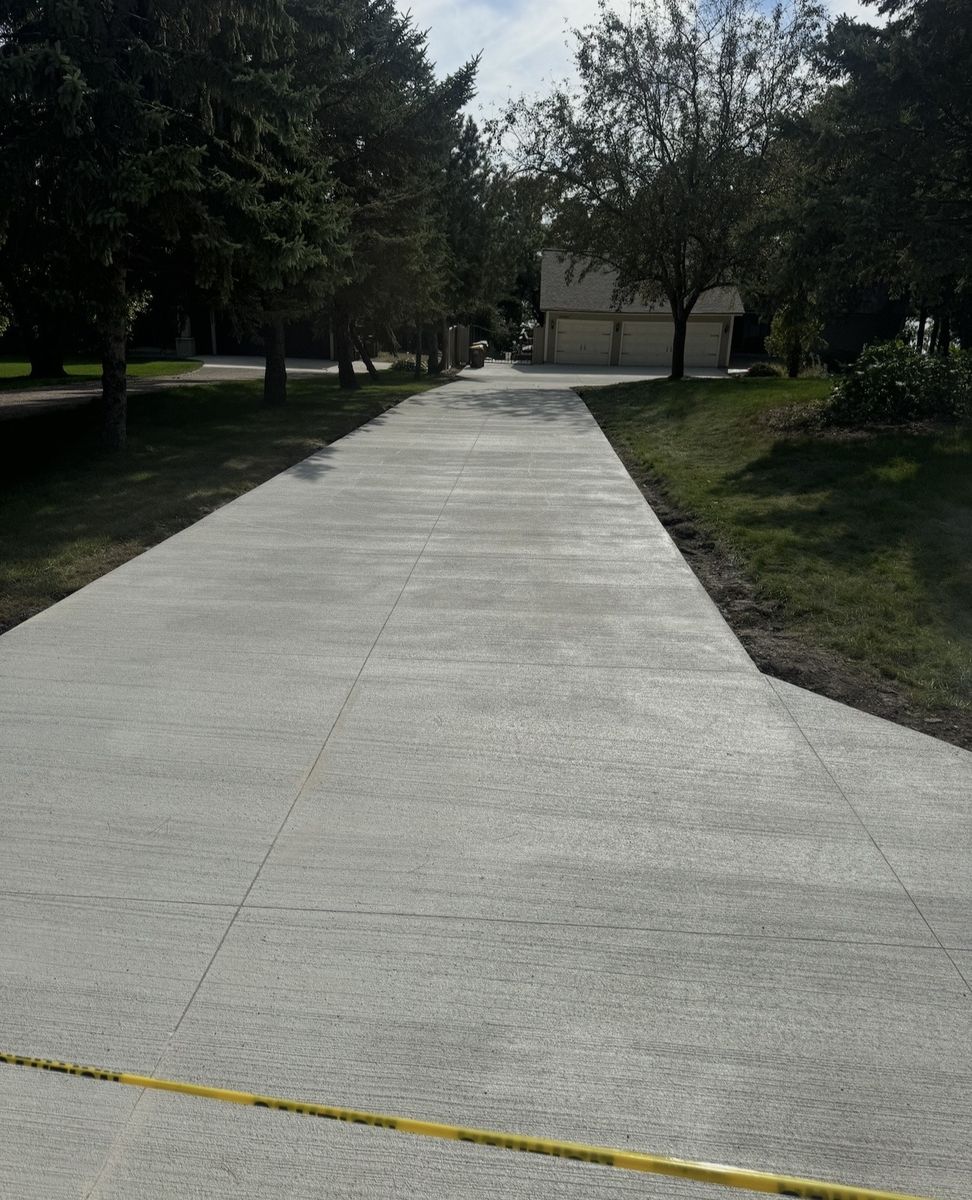 Long broom finished concrete driveway leading to a detached garage