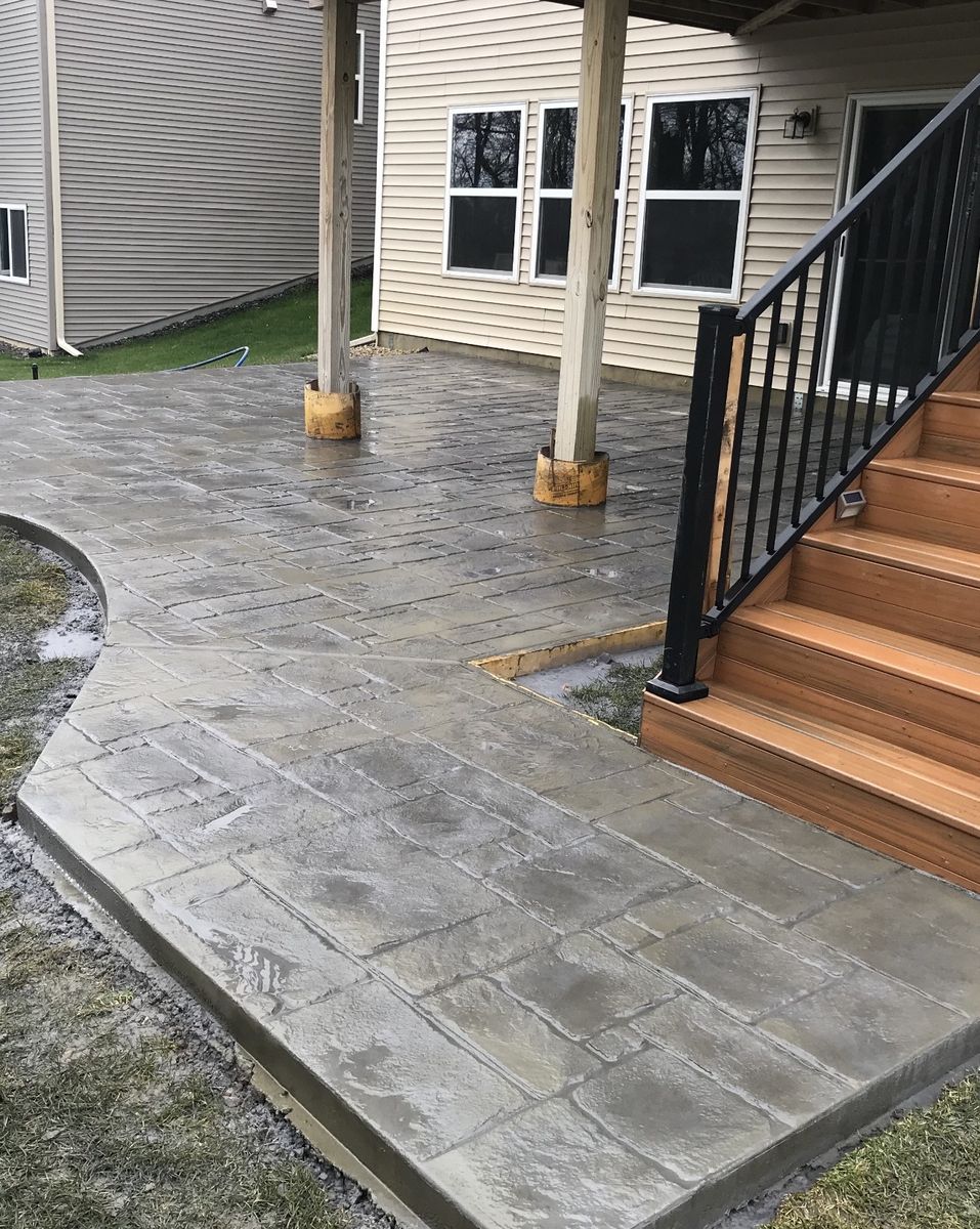 Stamped concrete patio wrapped around deck posts and steps with a curved walkway