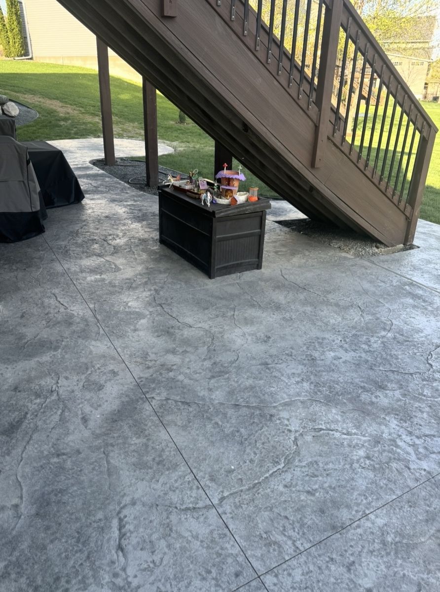 Seamless stone texture stamped concrete patio poured under a deck staircase
