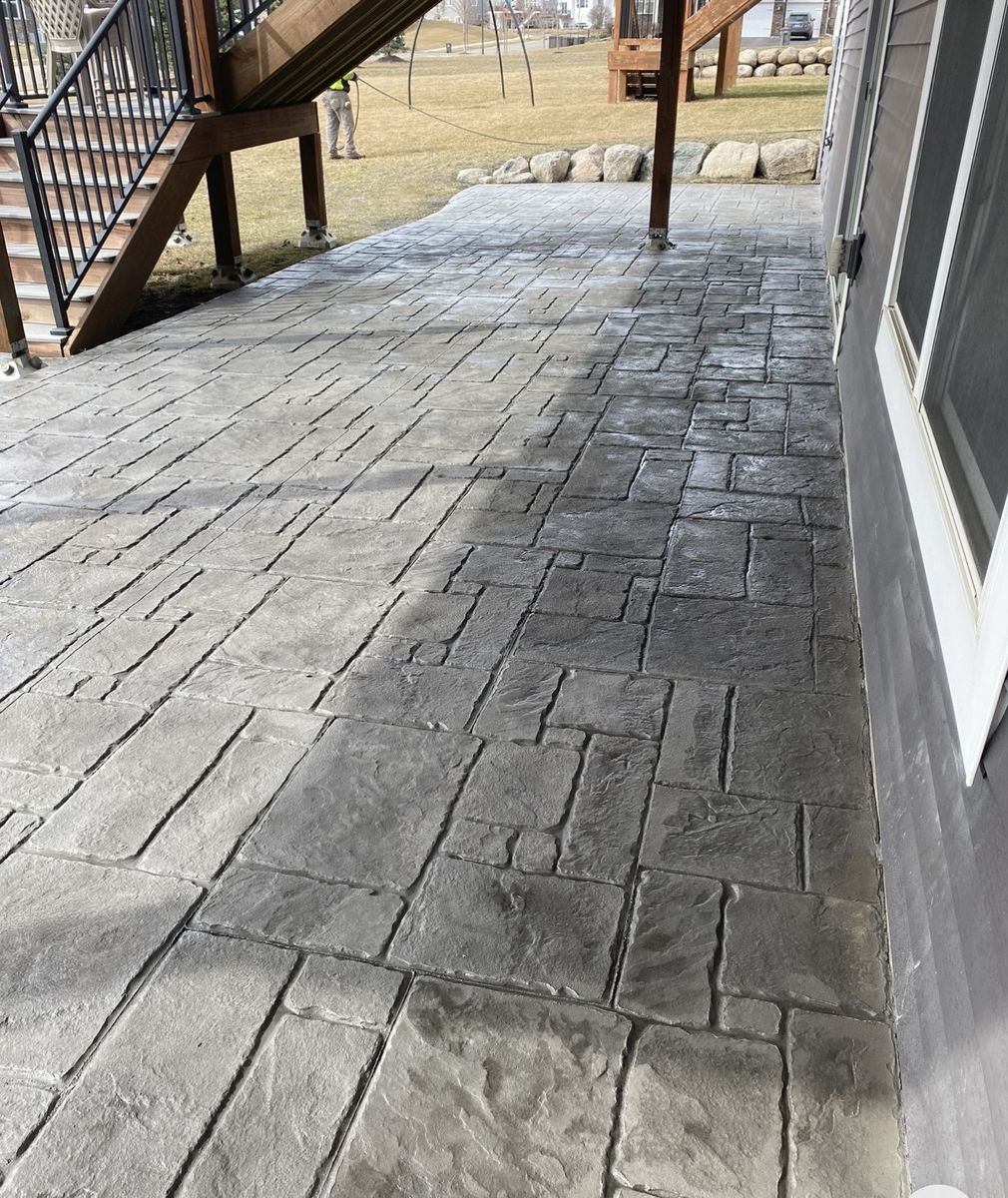 Long stamped concrete patio running the back of a walkout home under the deck